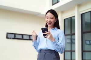 A business woman is smiling and holding a cell phone. She is happy cheerful photo