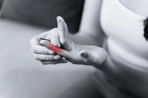 Woman suffering from hand and finger joint pain with red highlight. photo