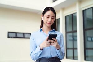 un negocio mujer es utilizando el inteligente teléfono mientras en pie fuera de foto