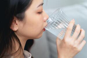 cerca arriba Disparo de un mujer Bebiendo agua desde un vaso. saludable, comida y bebida concepto. foto