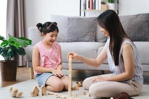 un mujer y un pequeño niña son jugando con bloques foto