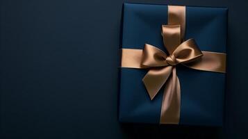 Dark blue gift box with elegant gold ribbon on dark background. Greeting gift with copy space for Christmas present, holiday or birthday photo
