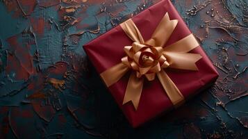 Dark red gift box with elegant gold ribbon on dark background. Greeting gift with copy space for Christmas present, holiday or birthday photo