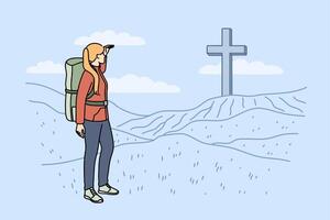 Woman pilgrim stands near large christian cross on hills during hike to sites of ancient cities vector