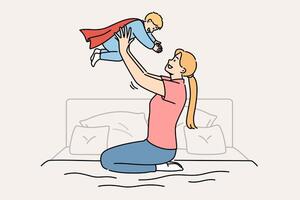 Happy mother lifts up newborn son in superhero costume, sitting on bed in bedroom vector