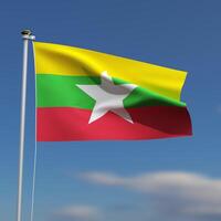 Burma Flag is waving in front of a blue sky with blurred clouds in the background photo