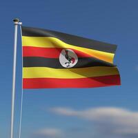 Uganda Flag is waving in front of a blue sky with blurred clouds in the background photo