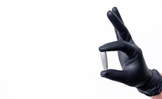 Titanium alloy bolts in hand in black latex gloves isolated on white background. Dental concept. photo