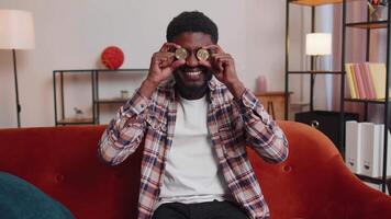 Man freelancer holding two gold coins BTC at home, successful developer programmer stock trader video