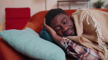 African american young man sleeping quietly in bedroom at home, smiling, lying on comfortable bed video