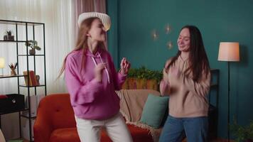 Happy two teenage girls siblings or bloggers couple dancing at home having fun enjoying trendy dance video