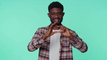 Smiling african american man makes heart gesture demonstrates love good sign feelings and sympathy video