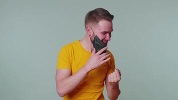 Young smiling man happily taking off medical mask and throws it away celebrating Coronavirus end video