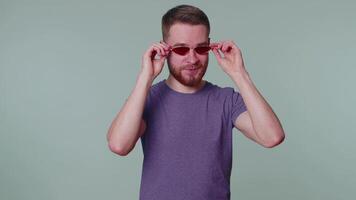 spielerisch glücklich Mann tragen Sonnenbrille blinkend Auge suchen beim Kamera mit lächeln, zwinkert, flirten video
