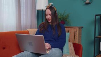 alegre joven mujer sentado en sofá, utilizando ordenador portátil ordenador personal compartir mensajes en social medios de comunicación solicitud video