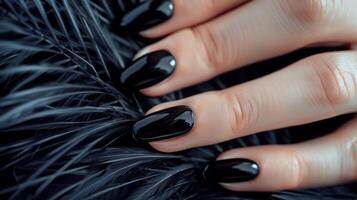 Glamour woman hand with luxury black color nail polish manicure on fingers, touching black feathers, close up photo