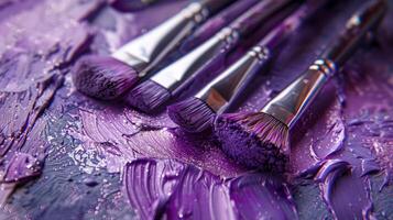 A collection of brushes set on a palette with shimmering violet paint photo