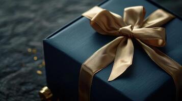 Dark blue gift box with elegant gold ribbon on dark background. Greeting gift with copy space for Christmas present, holiday or birthday photo