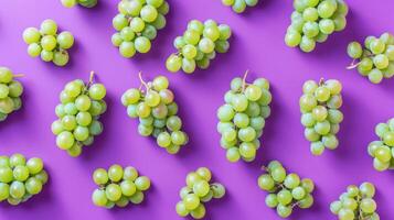 Fresh juicy grapes on a vibrant purple background, arranged in a top view flat lay style display. photo