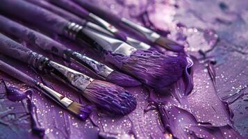 A collection of brushes set on a palette with shimmering violet paint photo