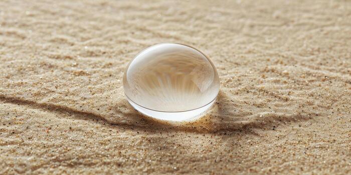 un pequeño, claro, redondo soltar de agua se sienta en un arenoso playa foto
