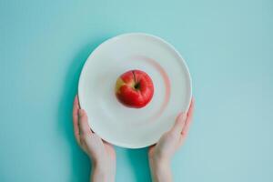 Single Red Apple Centered on White Plate Held by Hands photo