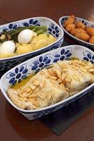 oven-baked cod with potatoes, eggs, broccoli, garlic and cod fritters on a platter photo