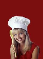 young smiling blonde chef with her colorful spoon posing on neutral background photo