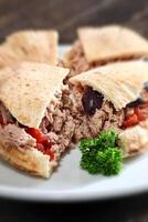 ciabatta bread sandwich with tuna, tomatoes and olives on plate photo