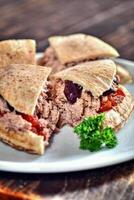 ciabatta bread sandwich with tuna, tomatoes and olives on plate photo