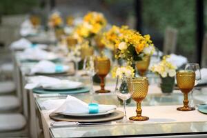 sofisticado almuerzo mesa preparar en yate club con platos, anteojos, flores y cuchillería foto