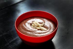 chocolate mousse in red plastic bowl with cocoa fruit slices photo
