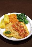 grilled fish fillet with potatoes, carrots, broccoli and tomato sauce photo