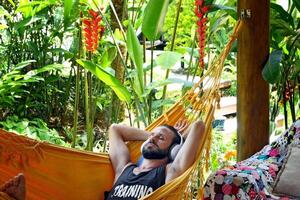 young man listening to music while resting in hammock photo