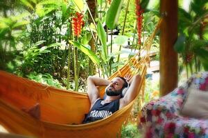 young man listening to music while resting in hammock photo