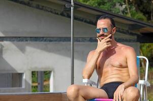 joven hombre disfrutando vacaciones a el playa y piscina foto