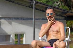 joven hombre disfrutando vacaciones a el playa y piscina foto