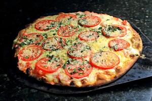 margherita Pizza viniendo fuera de el horno con queso, tomate salsa y albahaca foto