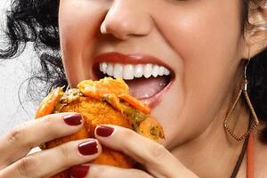 smiling brunette model with her acaraje, a Brazilian snack, in her hands photo