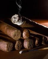 lit Cuban cigar on wooden table photo