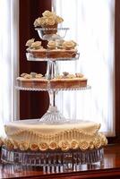 wedding cake decorated with flowers and small matching cupcakes to match on the plate photo