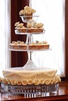 wedding cake decorated with flowers and small matching cupcakes to match on the plate photo