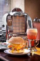 burger with cheese on plate and strawberry milkshake on old cafeteria table photo