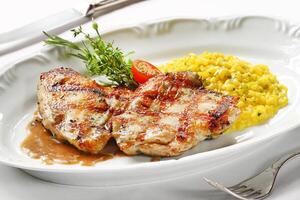 grilled chicken with risotto on plate photo