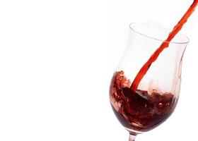 rojo vino siendo servido en un vaso en un blanco antecedentes foto