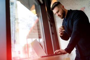 Professional indoor businessman working with computer. Office worker with laptop and coffee. photo