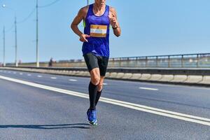 Athletic man jogging in sportswear on city road photo