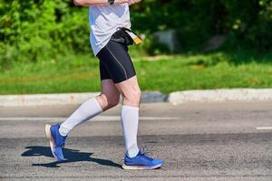 Athletic man jogging in sportswear on city road photo