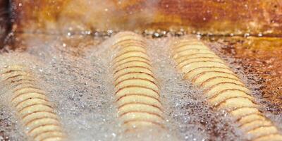 Cooking spiral fried potato in boiling oil, rich in fat and calories fast food, unhealthy delicious photo