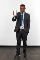 Smiling african american black man in business suit with smartphone mockup in hand, white background photo